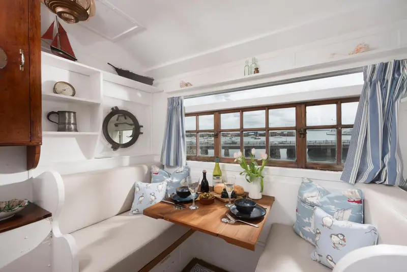 The dining nook, with cushioned benches and a table laid for two beside a wide harbour window